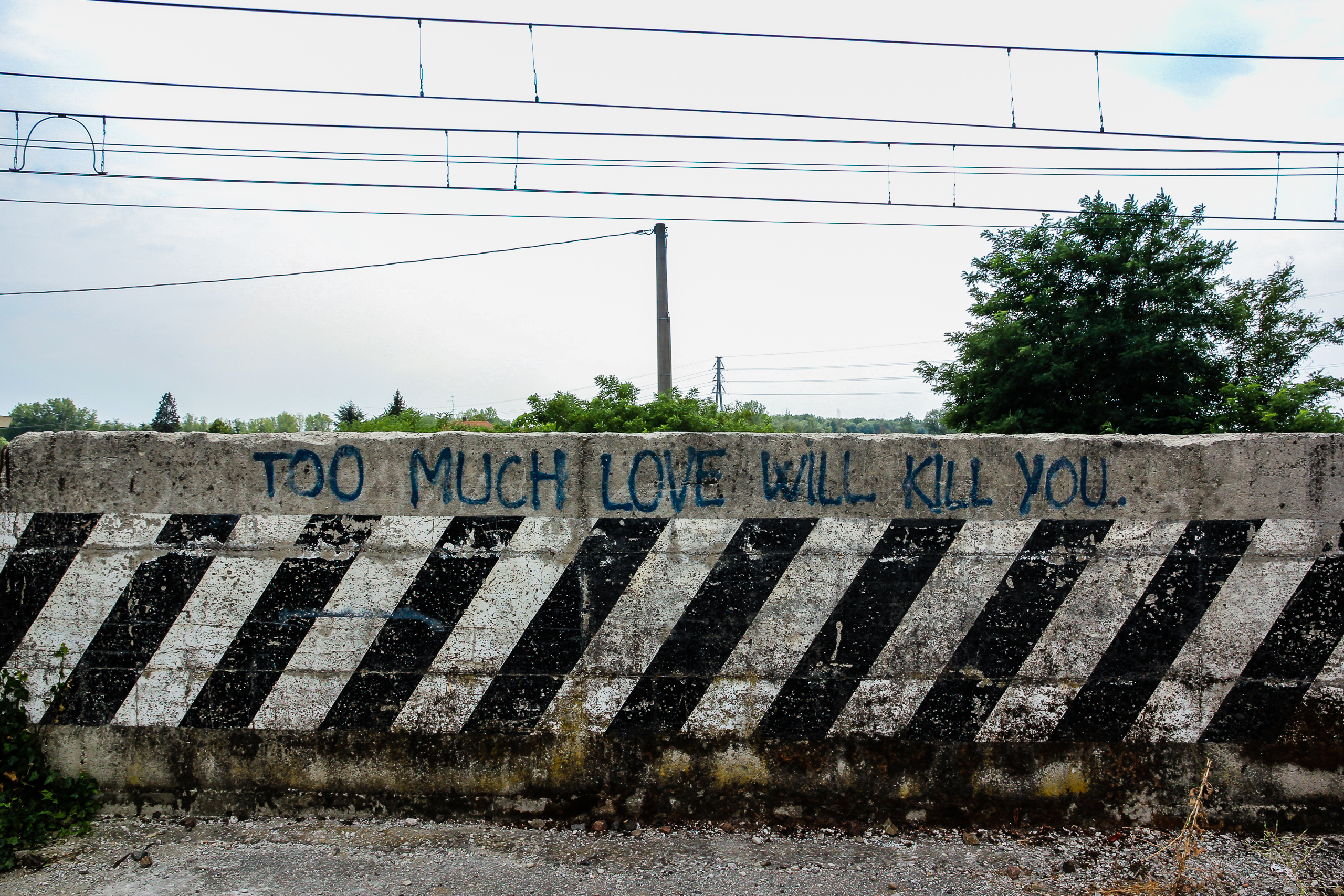 „Too much love will kill you" auf der Betonleitwand an der Bahn